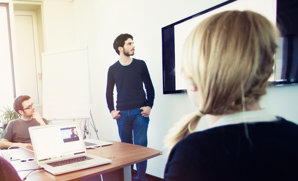 A man stands confidently in front of a diverse group of people, engaging them with his presence.