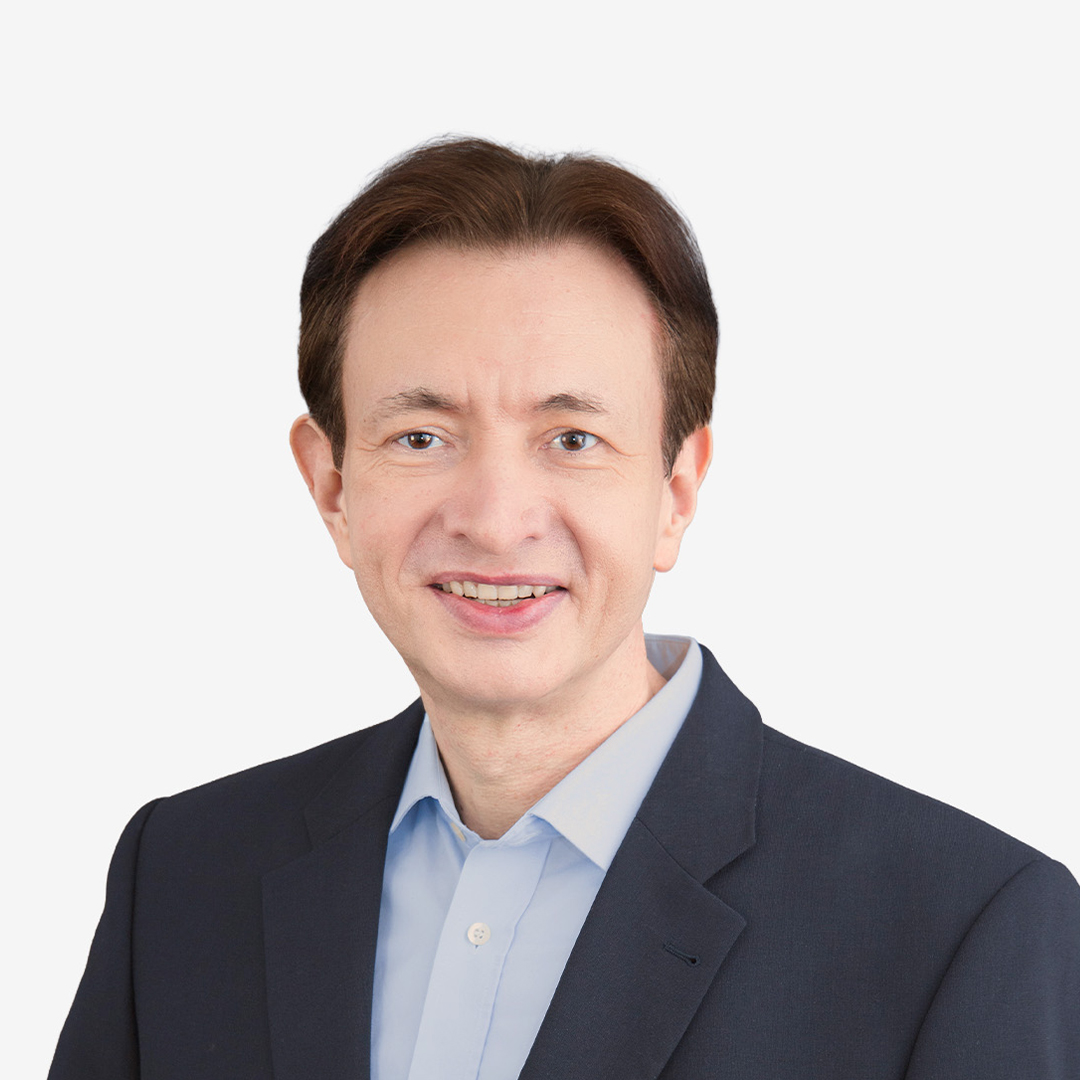 A man smiling in the foreground, wearing a blue shirt and a black jacket.