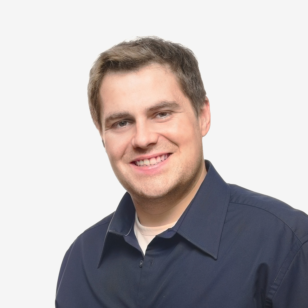 A man smiling in the foreground, a blue shirt.